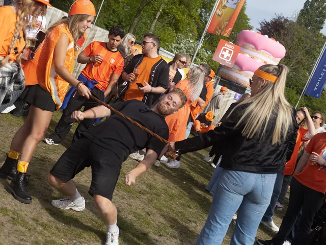 Dansende bezoekers in het oranje op het terrein